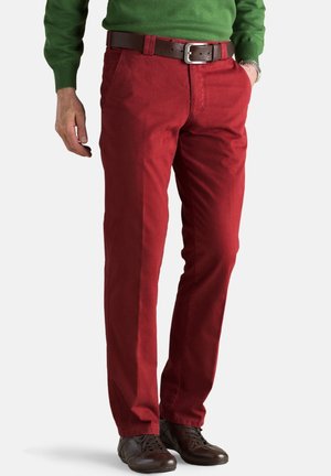Pantalons en coton rouge avec une coupe droite, des coutures détaillées, des poches avant et une ceinture en cuir marron. Associés à des chaussures marron foncé.