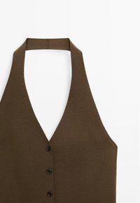 Top marrone senza maniche con un profondo scollo a V, caratterizzato da una texture a coste e cinque bottoni neri sulla parte anteriore.