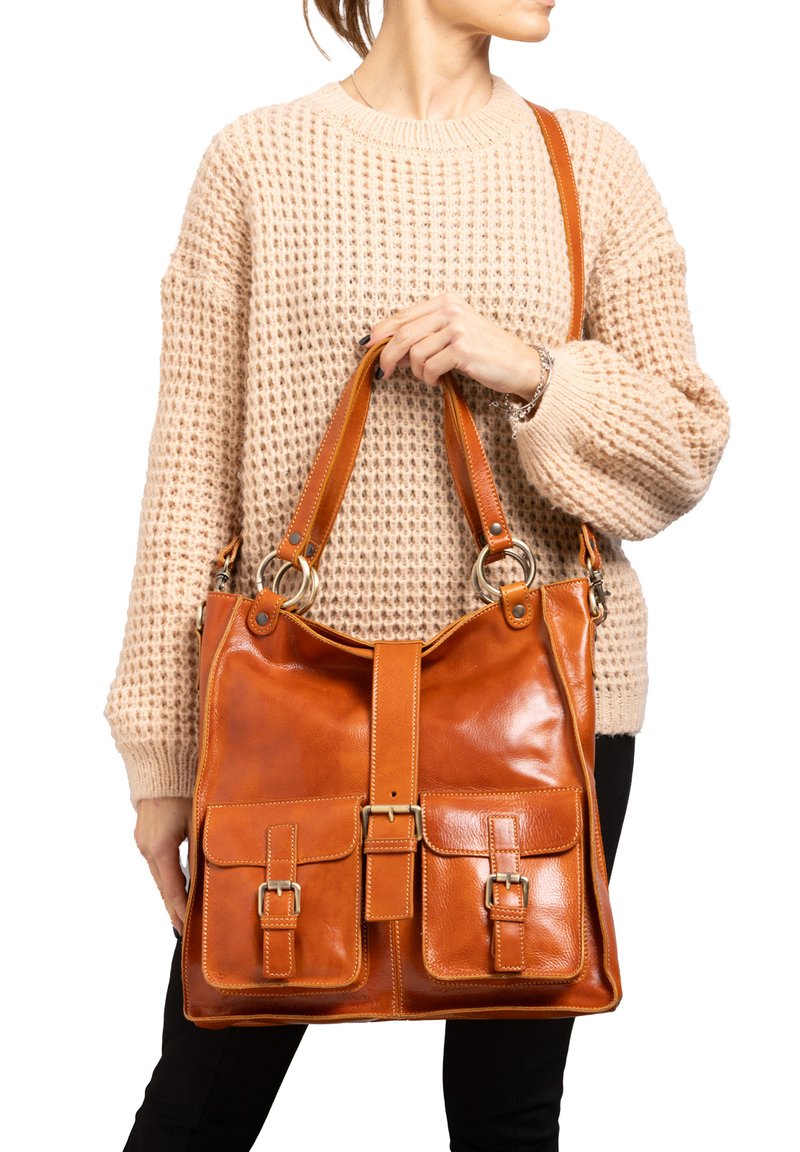 Bruine leren handtas met twee voorkleppen, gouden hardware-accenten en een brede schouderband. Glad textuur, rechthoekige vorm en centrale klep sluiting.