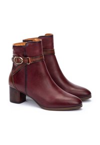 Bottines en cuir bordeaux avec un bout rond, une sangle décorative et une boucle, ainsi qu'un talon carré. Texture lisse et design minimaliste.