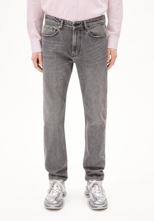 Graue Jeans aus Denim mit geradem Bein, ausgestattet mit Fronttaschen und subtilen Nähdetails. Getragen mit einem hellrosa Langarmshirt.