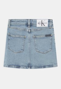 Saia de ganga em azul claro, com um cós, dois bolsos traseiros e um rótulo da Calvin Klein na parte de trás. A barra desgastada.