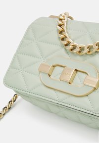 Pikowana zielona skórzana torebka na ramię z złotym łańcuchem i złotym zapięciem z prostokątnym wzorem.