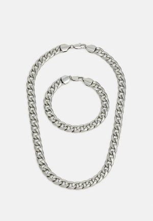 Metalli kettiga kaelakee ja käevõru komplekt. Hõbedane värv, paksud lingid, sile tekstuur, varustatud turvaliste lukudega. Mõlemal tükil on ühtlane disain.