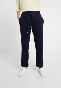 Marina blå byxor i bomull med resårmidja och snörning. Har två framfickor och en avslappnad passform.