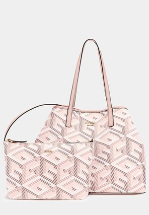 Sac cabas rose à motif géométrique avec pochette zippée assortie, tous deux ornés de logos dorés « GUESS » et anses doubles sur le sac.