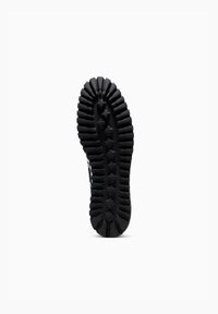 Suela de zapato de goma negra con táctiles pronunciados, que presenta un patrón en forma de estrella y detalles texturizados para un mejor agarre y tracción.