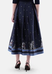 Marineblaue Midi-Rock aus satinartigem Stoff mit goldenen Punkten, versehen mit Hunderstickerei am Saum und einem gefalteten Design auf der Rückseite. Schwarze Absätze.