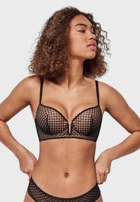 Black bra with a geometric mesh design, plunge cup shape, adjustable straps, and a soft texture. Features a central V detail between cups.