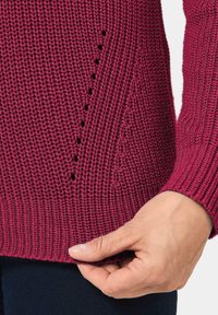 Burgunderfarbener Strickpullover mit einem strukturierten Muster und offenen Maschen an der Seite. Gerippter Saum und Bündchen, angenehme Haptik.
