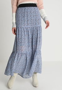 Jupe midi fluide bleue à fleurs avec un design en étages, dotée d'une ceinture élastique noire. Fabriquée à partir d'un tissu léger avec des motifs floraux délicats.