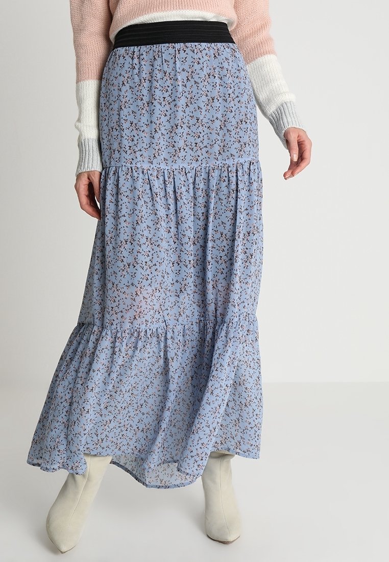 Jupe midi fluide bleue à fleurs avec un design en étages, dotée d'une ceinture élastique noire. Fabriquée à partir d'un tissu léger avec des motifs floraux délicats.