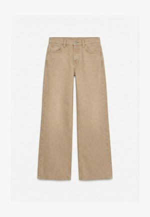 Μπεζ τζιν με ίσιο ύψος ποδιού, κούμπωμα με κουμπί και φερμουάρ μπροστά, μπροστινές και πίσω τσέπες και θηλιές για ζώνη σε λευκό φόντο.