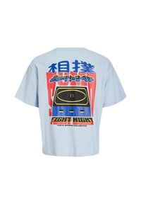 T-shirt di cotone azzurro con una grande stampa grafica che presenta elementi audaci in rosso, blu e nero, testo e un motivo circolare.