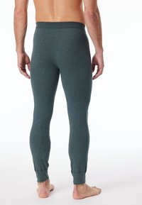 Herren Leggings in Dunkeltürkis, aus weichem Stoff mit glatter Textur. Mit einem dehnbaren Bund und enganliegenden Abschlüssen an den Knöcheln.