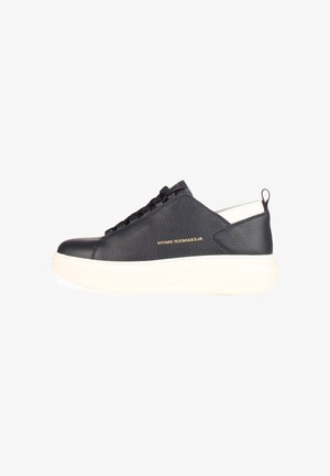 Zwarte lage sneaker van leer met dikke witte zool, zwarte veters en gouden "Alexander Smith" merknaam aan de zijkant.