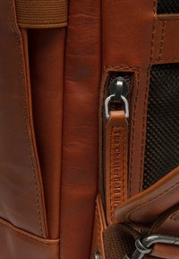 Sac en cuir marron avec une finition texturée, doté d'une fermeture éclair en métal argenté, d'un accent en tissu tissé et d'un logo embossé.