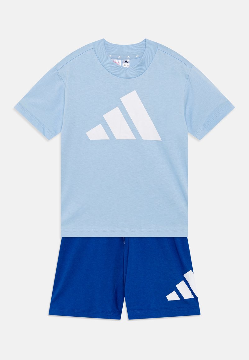 T-shirt di cotone azzurro chiaro con un grande logo bianco. Abbinato a pantaloni shorts blu con un accento di logo bianco. Tessuto morbido, vestibilità casual.