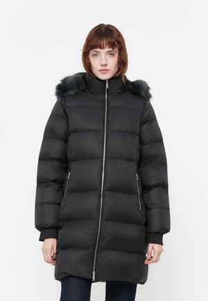 Zwarte pufferjas met een rits aan de voorkant, voorzien van een capuchon met nepbont, zijzakken en een gestikt ontwerp voor isolatie en warmte.