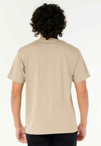 Camiseta corta de manga en color beige claro con cuello redondo, fabricada con una tela suave y con un diseño simple sin patrones ni acentos visibles.