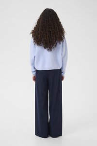 Světlomodrý pletený svetr s volnějším střihem, doplněný tmavě modrými širokými kalhotami. Má texturovanou látku a žebrované manžety.