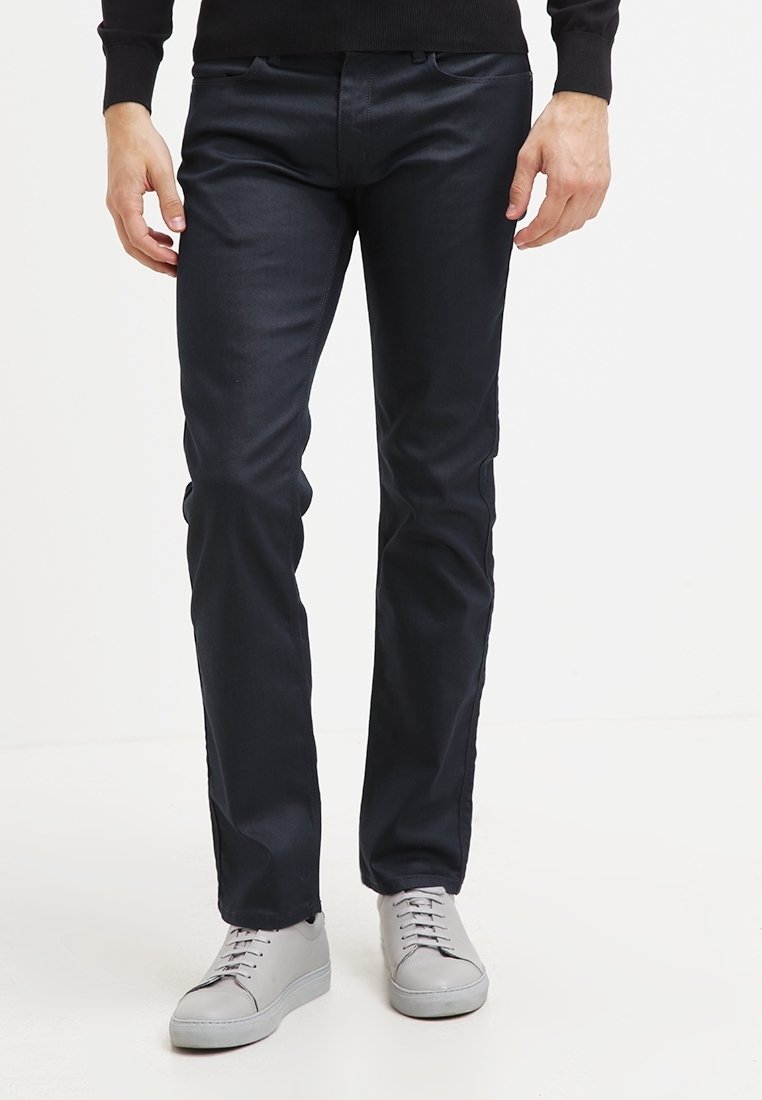 Marinblå byxor i slim fit, tillverkade av en mjuk textil, med en klassisk design som inkluderar framfickor och i kombination med ljusgrå sneakers.