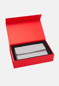 Light gray Valentino wallet with gold logo inside red box with black foam lining on white background.