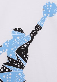 Sylwetka osoby unoszącej jedną rękę z piłką, wypełnioną niebieskimi i czarnymi wzorami geometrycznymi oraz białymi kropkami.