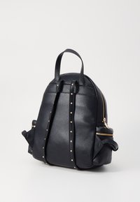 Zwarte leren rugtas met een gestructureerde afwerking, met gouden hardware, zijritsen en studded accenten op de schouderbanden.