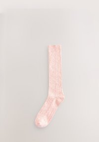 Lichtroze gebreide sok met een geribbelde boord, een gladde textuur en een lengte tot halverwege de kuit. Eenvoudig ontwerp zonder patronen of extra versieringen.