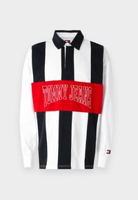 Long-sleeve polo shirt in white, black, and red strips. Features a large red band with "TOMMY JEANS" logo in white. Button-down collar.