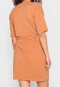 Rustańcza sukienka t-shirtowa z krótkimi rękawami. Posiada marszczone detale po bokach oraz luźny krój. Wykonana z miękkiej, oddychającej tkaniny.