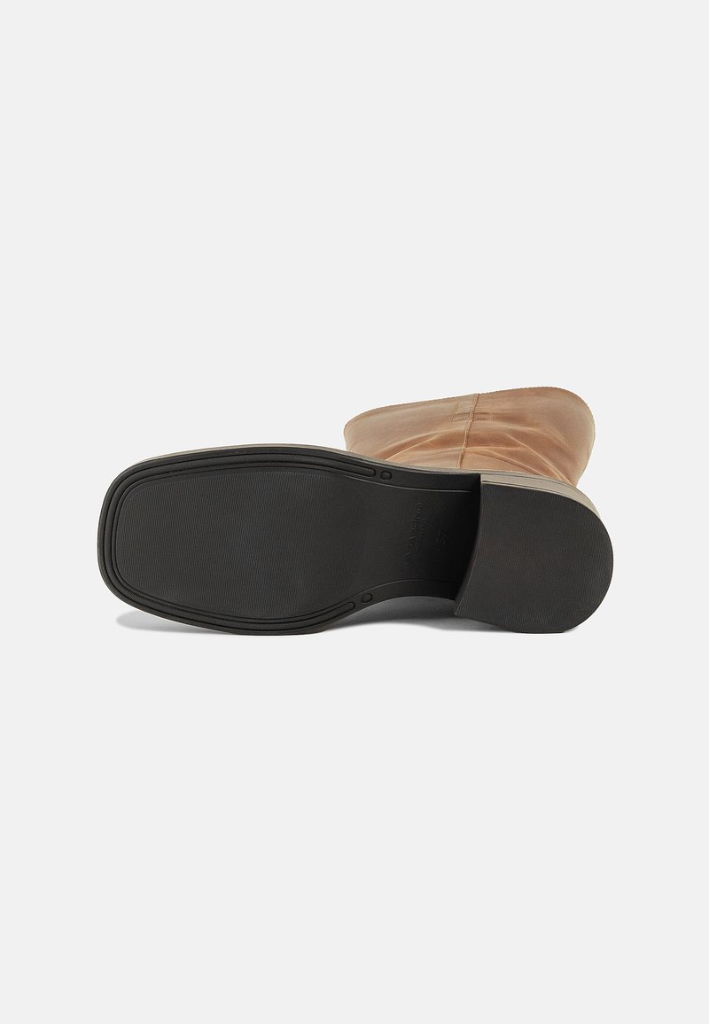 Stivaletto in pelle tan con tomaia liscia, punta rotonda e suola in gomma nera texturizzata. Presenta un dettaglio di cucitura lungo i lati.