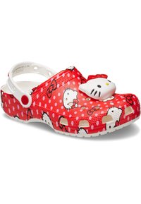 Zuecos rojos con lunares blancos, que presentan un diseño de Hello Kitty y un acento de moño en 3D. Hechos de un material liviano, con agujeros de ventilación y tira de talón.