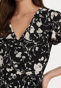Černé květinové šaty s bílými růžovými vzory, V- výstřih, nabírané rukávy, černé knoflíky a zavázaný pás, vyrobené z lehkého materiálu.