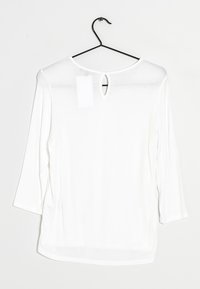 Haut blanc léger avec des manches trois-quarts, un col arrondi et un détail en forme de clé à l'arrière. Texture lisse, design minimaliste.