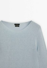 Jasnoniebieski sweter z dzianiny o okrągłym dekolcie. Miękka tekstura, długie rękawy i subtelne detale na ramionach. Widoczne metki wewnątrz.