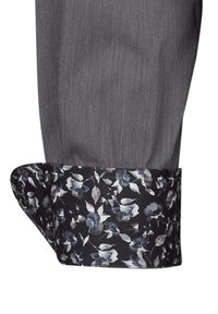 Cuff della camicia a righe grigie con una stampa floreale in nero, bianco e tonalità di blu sul rivestimento interno, con bordo arrotondato.