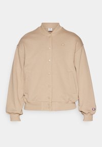 Felpa beige con bottoni, orlo e polsini a costine, due tasche laterali e un piccolo logo sul petto. Tessuto morbido, vestibilità comoda.