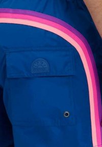 Pantaloni corti blu con una tasca laterale, presentano righe d'accento rosa e viola lungo il lato. Il materiale appare leggero e liscio.
