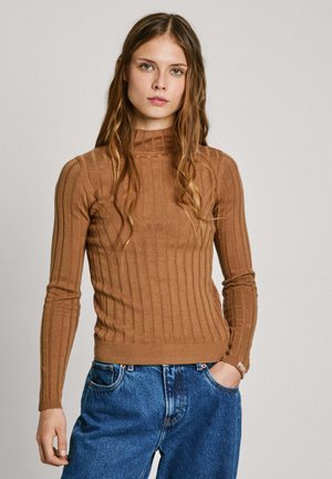 Maglione a collo alto marrone a costine con maniche lunghe, silhouette aderente e orlo a costine. Abbinato a jeans in denim blu a vestibilità ampia.