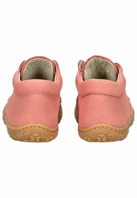 Due scarpe per bambini di colore rosa, realizzate in pelle con una texture morbida, di forma arrotondata, suole in gomma marrone chiaro e fodera interna beige.