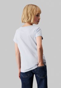 Camiseta de algodón azul claro con mangas cortas, escote redondo y una textura suave, combinada con vaqueros de mezclilla azul oscuro.