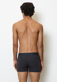 Boxers ajustés à côtes gris foncé avec une taille élastique, vus de dos. Le tissu semble légèrement texturé et ajusté.