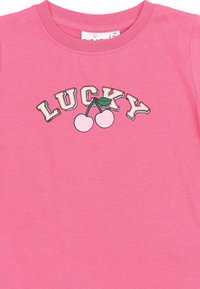Tricou din bumbac roz, cu decolteu rotund, având inscripția "LUCKY" și un grafic cu cireșe în centru. Material moale, design casual.