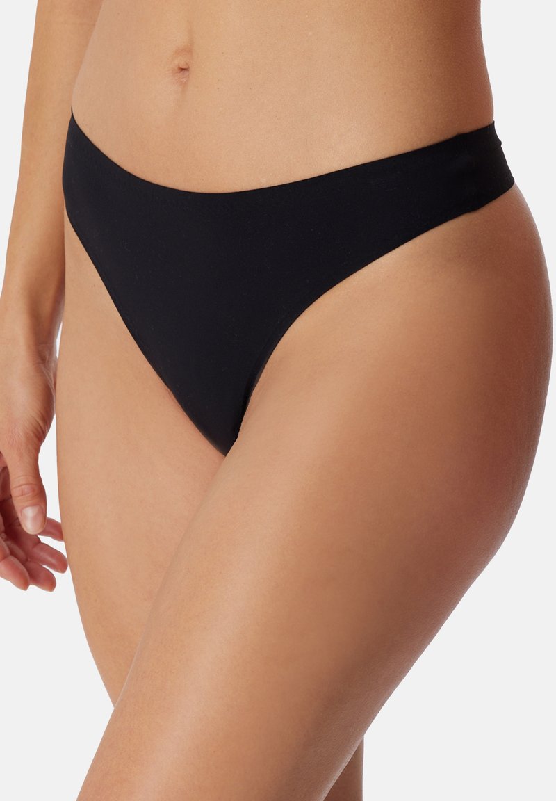 Bas de bikini noir en tissu extensible, présentant un design taille basse et une couverture minimale. Texture lisse sans motifs visibles.