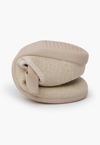 Scarpa slip-on in tessuto beige con una forma arrotondata, suola morbida e imbottita, e un design testurizzato. Presenta una fascetta laterale per una vestibilità sicura.