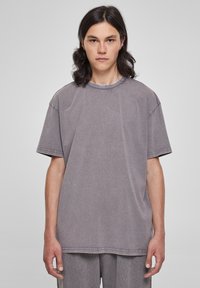 T-shirt supradimensionat gri, fabricat dintr-un material moale, cu guler rotund, umeri lăsați și detalii subtile de cusătură. Design simplu, fără embellishments.