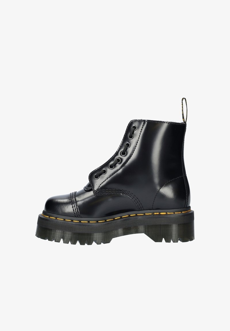 Botte de combat en cuir noir à haute brillance, semelle épaisse striée, couture jaune, languette de traction et six paires d'œillets pour lacets, vue de côté.