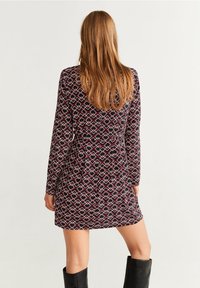 Sukienka z długim rękawem w geometryczny wzór w kolorach bordowym, niebieskim i białym. Wykonana z miękkiego materiału, do kolan, o luźnym kroju.